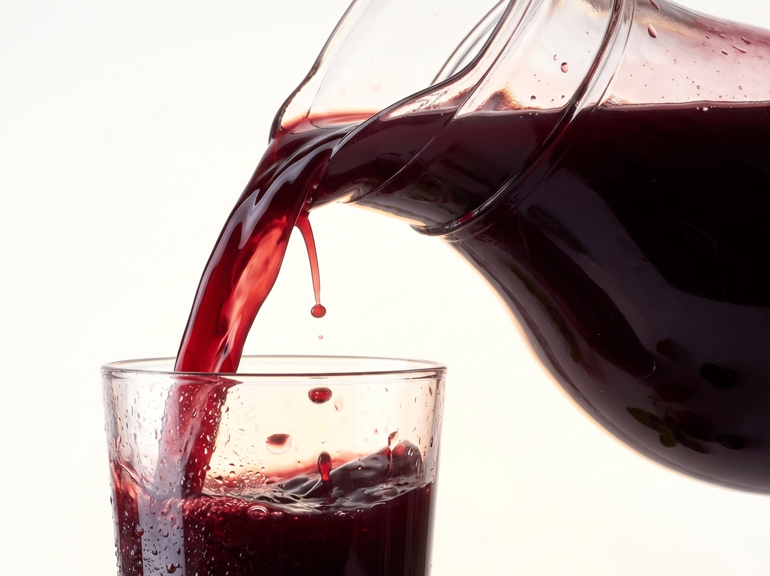 NUI NONI Original: dunkelrotes Getränk wird aus einer Glaskanne in ein Glas gegossen